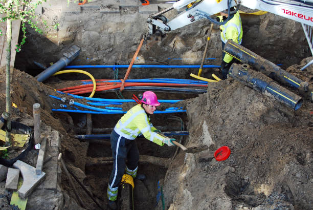 Workers installing fiber conduit in an underground trench