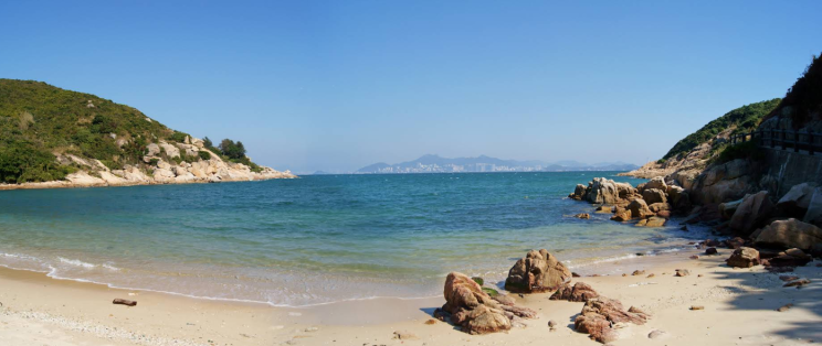 A quiet Hong Kong island beach, the city skyline faint across the water