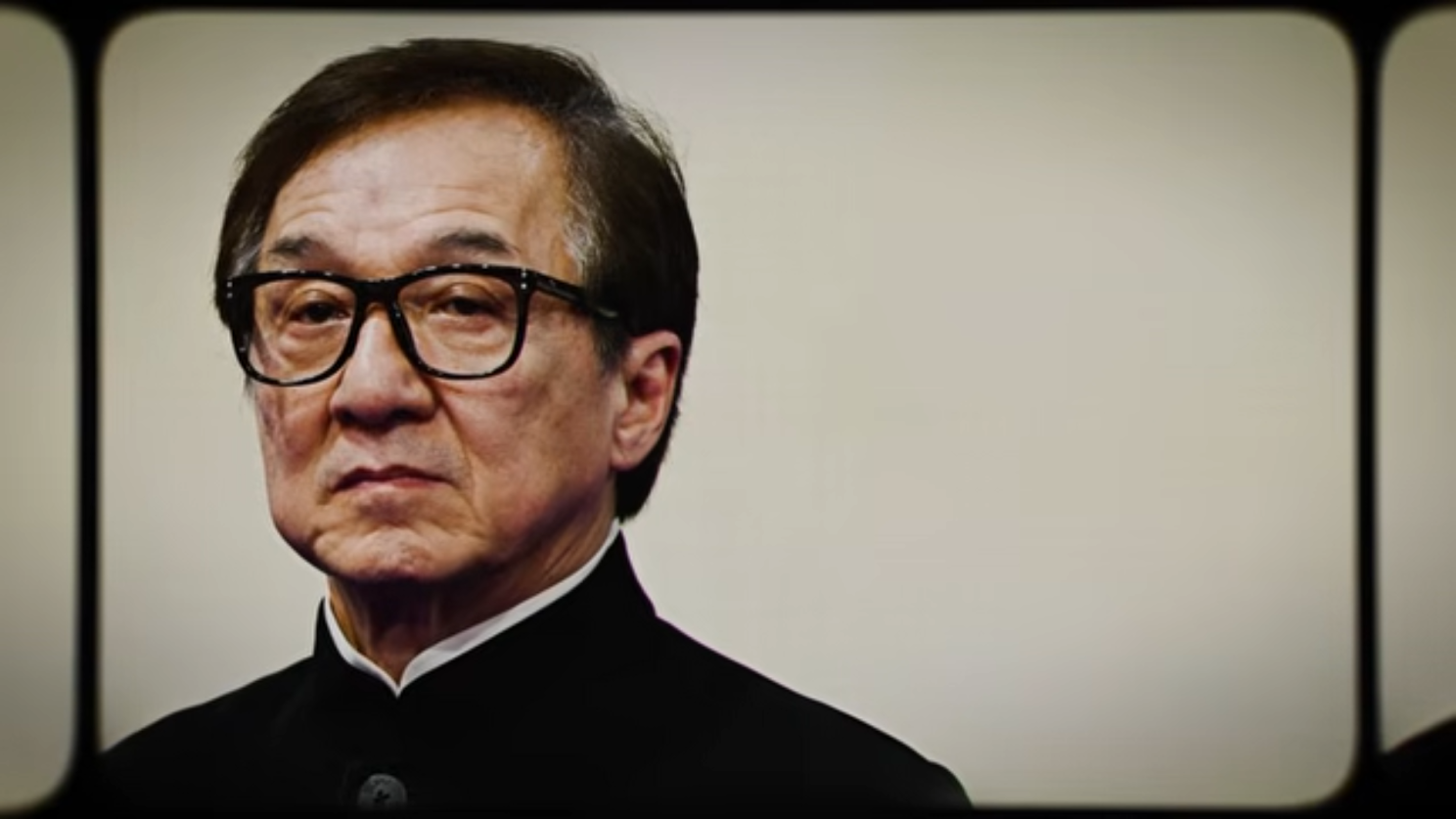 A film-frame close-up of Jackie Chan looking directly at the camera