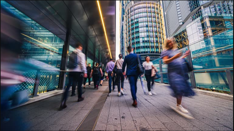 Pedestrians moving through a busy modern city, motion-blurred